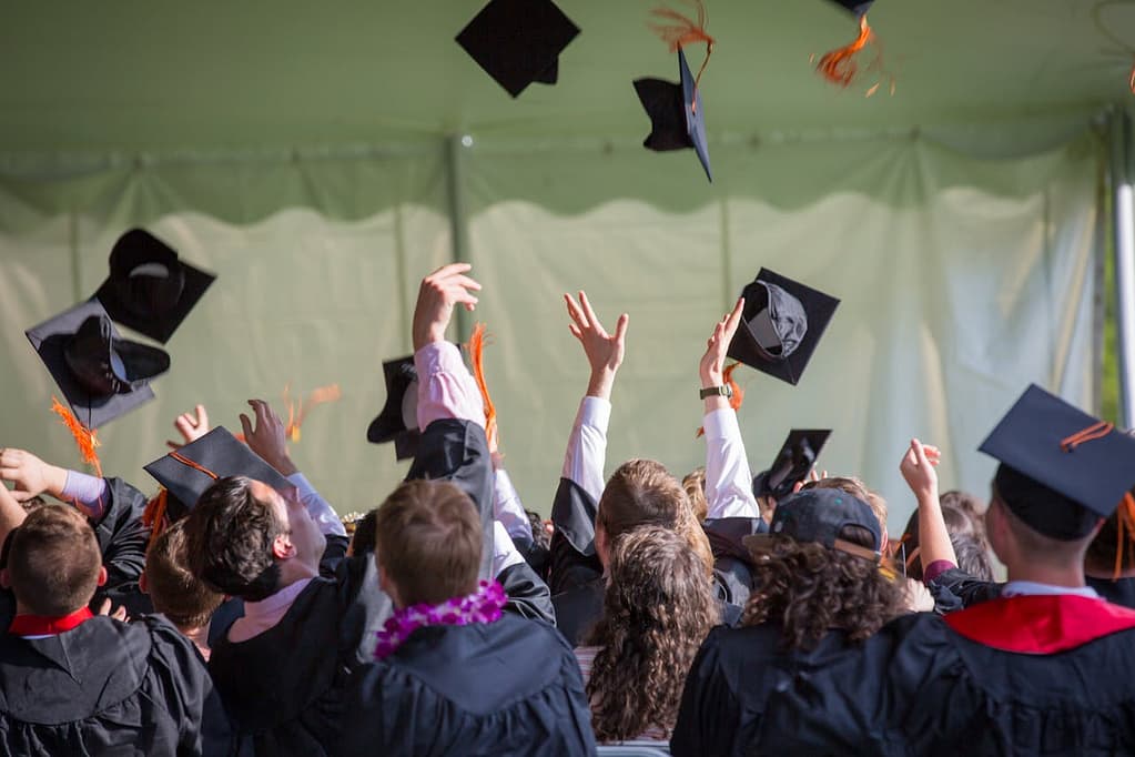 Home Group of graduates celebrating by tossing caps into the air during a graduation ceremony.