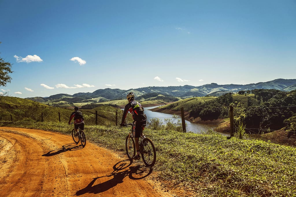 ULTIMATE FITNESS GUIDE FOR MEN AND BOYS: BUILD STRENGTH, eNERGY & CONFIDENCE NATURALLY Two cyclists riding on a dirt trail with stunning mountain views and clear skies.