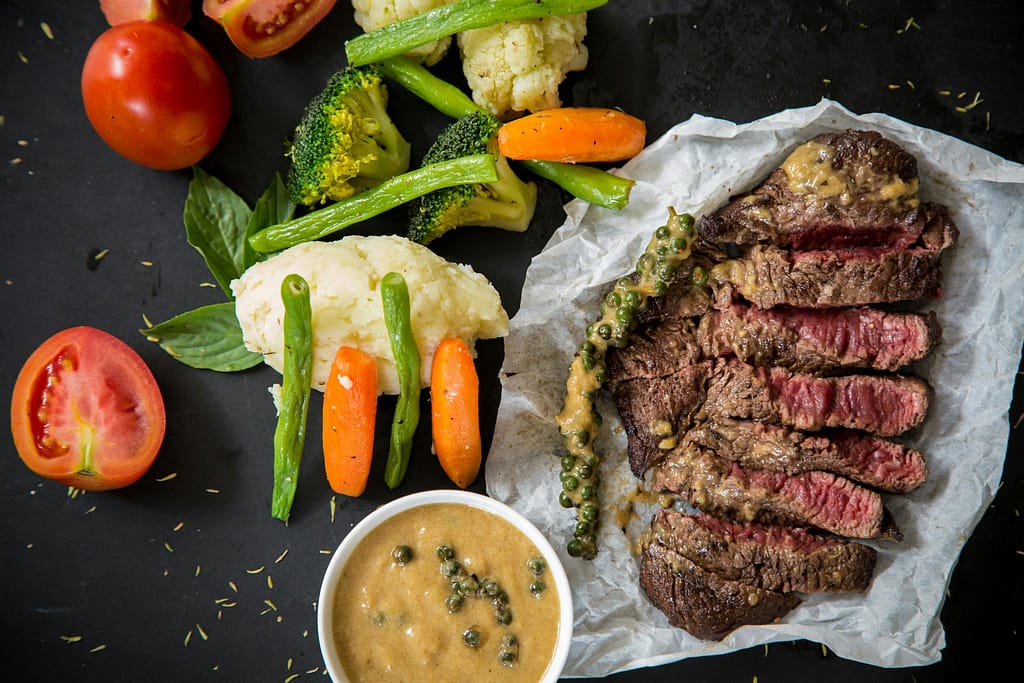 10 Natural and effective ways to gain weight fast in 2025 Grilled steak served with fresh vegetables and pepper sauce, presenting a colorful and appetizing meal.